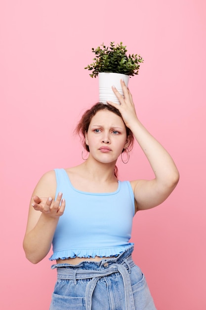 Hermosa mujer en una camiseta azul y pantalones cortos un fondo rosa maceta inalterado