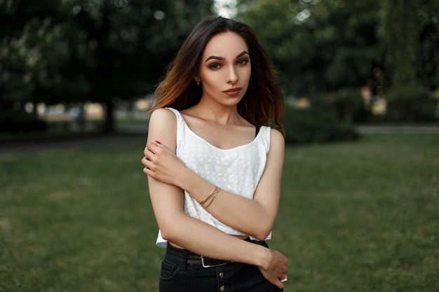 Hermosa mujer en una camiseta blanca posando en el parque en un día de verano