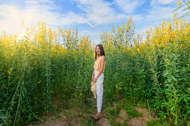 Hermosa mujer con un campo de flores Sunhemp