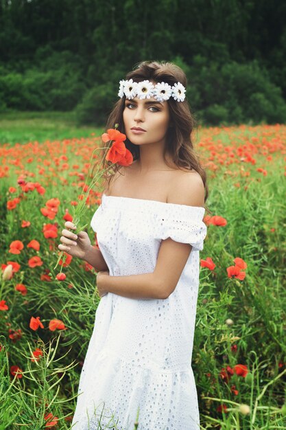 Hermosa mujer en campo con muchas flores de amapola