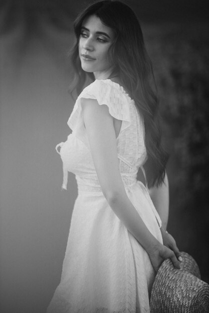 Hermosa mujer en el campo con sombrero y vestido blanco