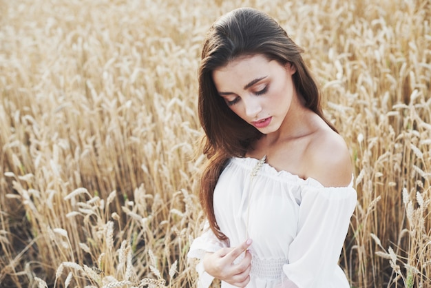 Hermosa mujer en un campo de trigo con un vestido blanco, una imagen perfecta en el estilo de vida