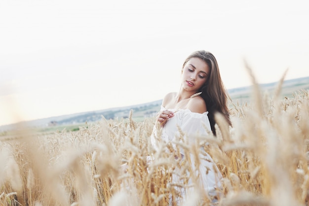 Hermosa mujer en un campo de trigo con un vestido blanco, una imagen perfecta en el estilo de vida