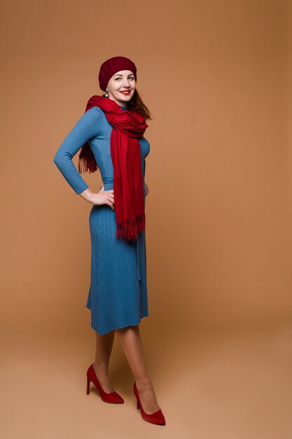 Hermosa mujer caucásica con cabello medio oscuro en vestido azul, sombrero rojo y pañuelo rojo