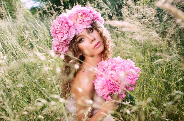 hermosa mujer caucásica con una corona de peonías rosas en la cabeza Concepto de hada de flor de primavera