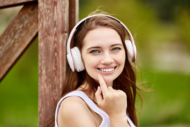 Hermosa mujer caucásica está escuchando música al aire libre con auriculares inalámbricos