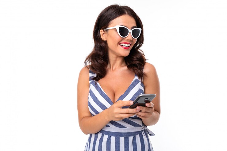 Hermosa mujer caucásica con gafas de sol comunicarse con personas en el teléfono y riendo, imagen aislada sobre fondo blanco