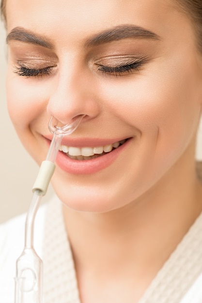 Hermosa mujer caucásica joven feliz recibiendo inhalador nasal con aceite esencial sonriendo en un spa