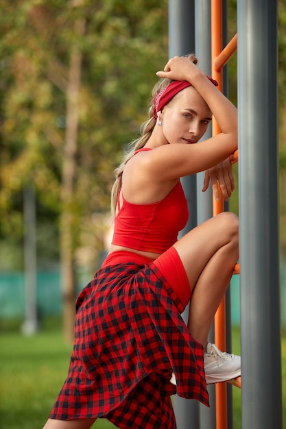 Hermosa mujer caucásica joven en ropa de fitness haciendo ejercicios en un parque.