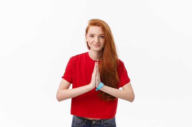 Hermosa mujer caucásica joven, tomados de la mano en namaste u oración, manteniendo los ojos cerrados mientras practica yoga.