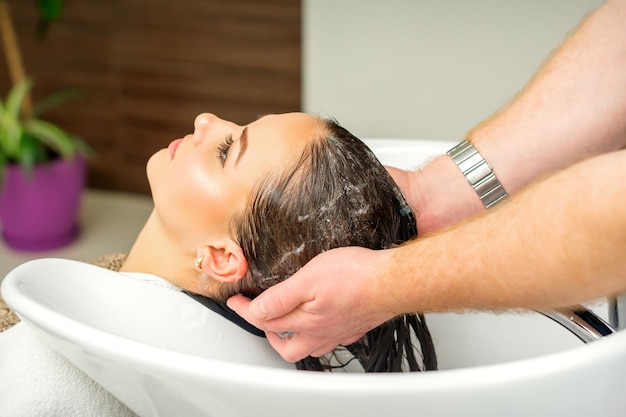 Hermosa mujer caucásica lavarse el cabello en un salón de belleza.