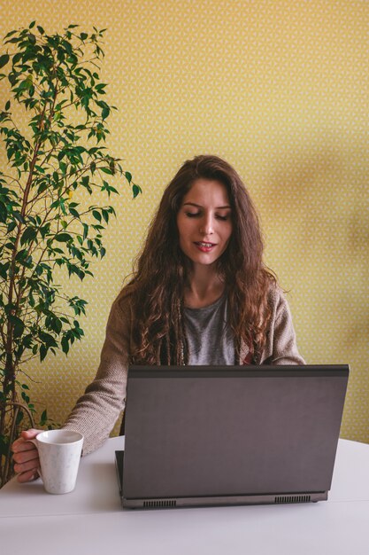 Hermosa mujer caucásica usando laptop y tomando café