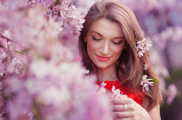 Hermosa mujer cerca del árbol de primavera floreciente