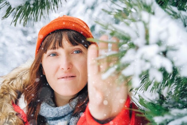 Hermosa mujer con una chaqueta roja y un sombrero en un bosque nevado de invierno