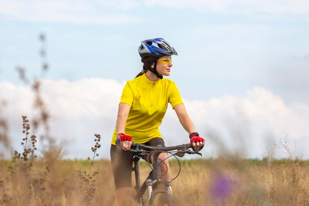 Hermosa mujer ciclista monta en el campo en bicicleta. Estilo de vida saludable y deporte.