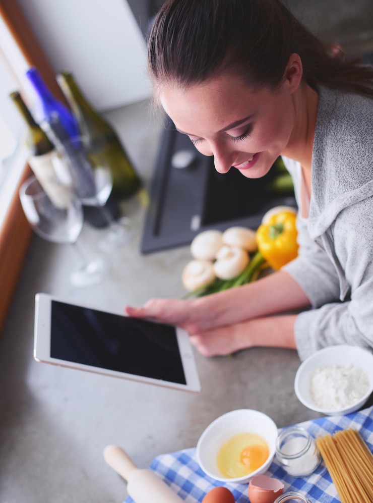 Foto hermosa mujer cocinando pastel en la cocina de pie cerca del escritorio
