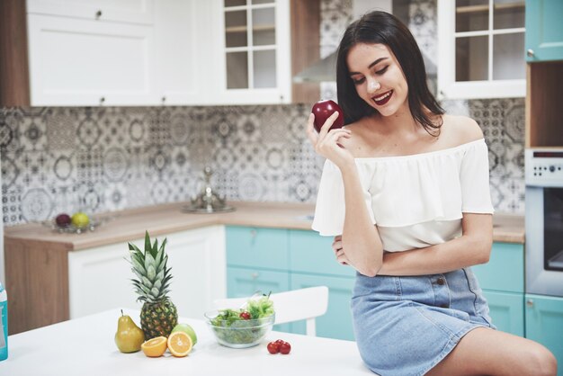 Foto hermosa mujer con comida sana fruta en la cocina.