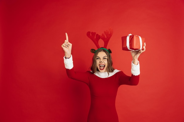 Hermosa mujer como ciervos de Navidad aislado en concepto de superficie roja de vacaciones de humor de invierno de año nuevo