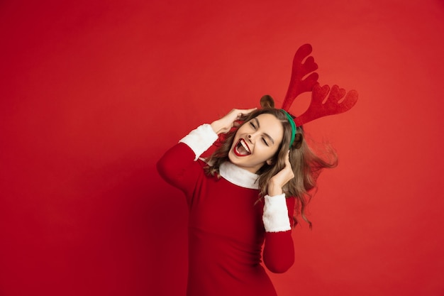 Hermosa mujer como ciervos de Navidad aislado en pared roja