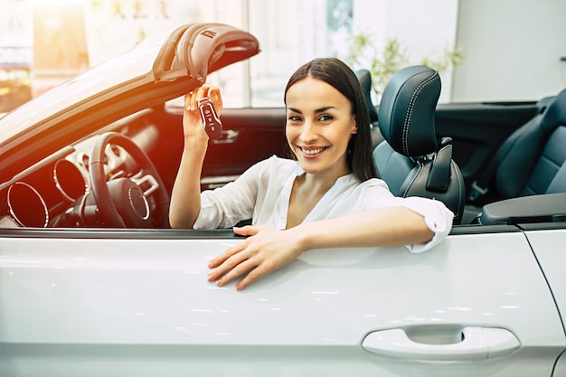 Hermosa mujer comprando un auto nuevo para trabajar y viajar en el cliente de la chica del concesionario con llave en mano