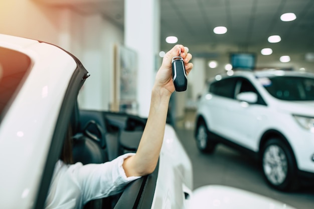 Hermosa mujer comprando un auto nuevo para trabajar y viajar en el cliente de la chica del concesionario con llave en mano