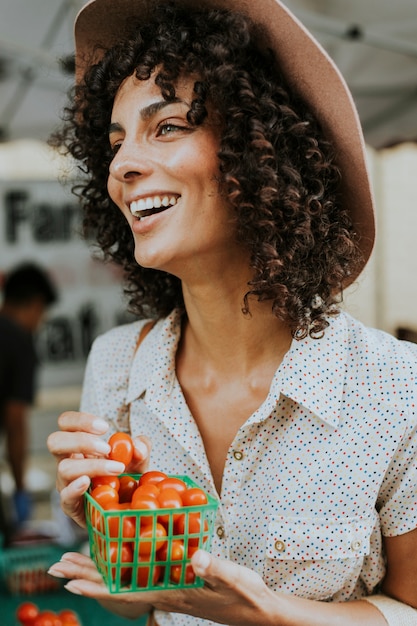 Hermosa mujer comprando tomates en un mercado de agricultores