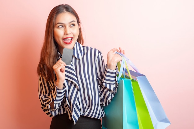 Hermosa mujer de compras está sonriendo sobre fondo rosa