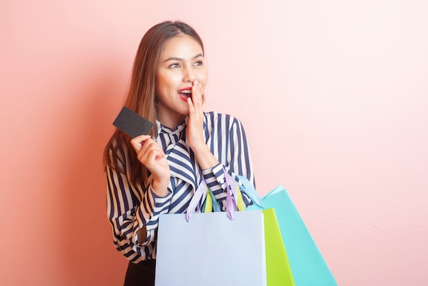 Hermosa mujer de compras está sonriendo sobre fondo rosa