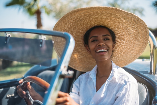 Hermosa mujer conduciendo un coche descapotable vintage