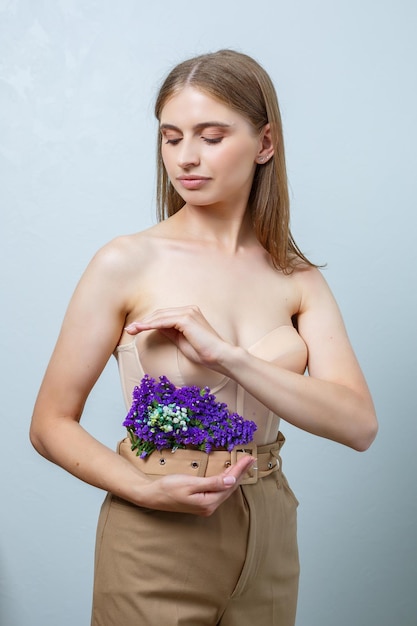 Hermosa mujer confiada sosteniendo flores frescas de primavera en sus manos Flores frescas en manos de una mujer rubia