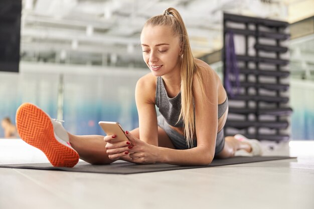 Hermosa mujer delgada caucásica está haciendo entrenamiento de estiramiento en un estudio moderno y ligero