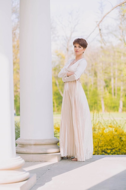 hermosa mujer delgada con un vestido largo de noche se encuentra en las columnas