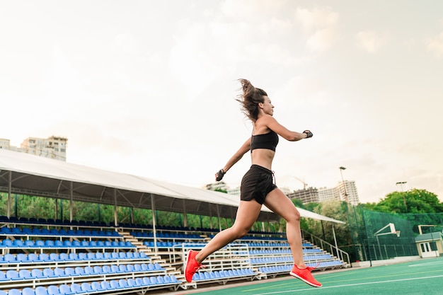 Hermosa mujer deportiva en forma saltando en el estadio en el aire