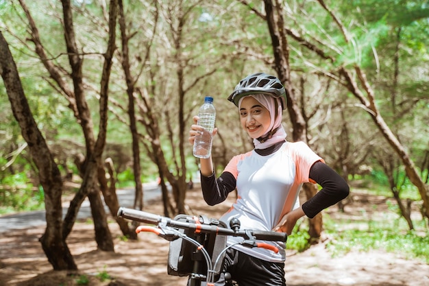 Hermosa mujer deportiva en hijab sosteniendo botella