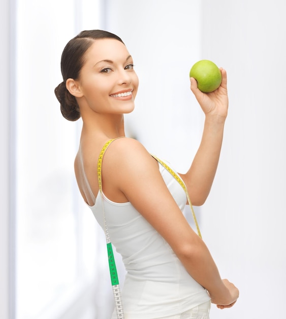 Hermosa mujer deportiva con manzana y cinta métrica