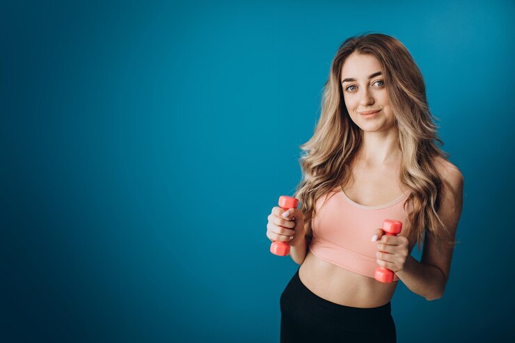 Hermosa mujer deportiva de pie en estudio con pesas