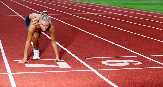 Hermosa mujer deportiva preparándose para correr en la línea de salida