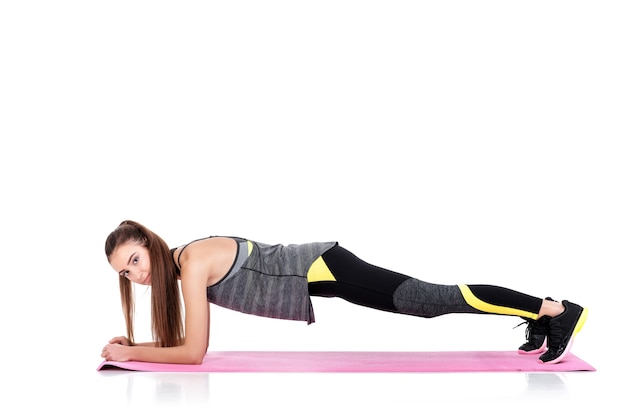 hermosa mujer deportiva en ropa deportiva hace ejercicios de fitness Mat aislado sobre fondo blanco. tablón