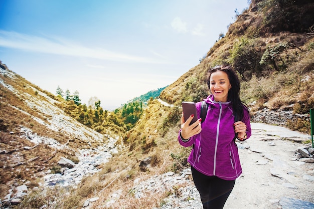 Hermosa mujer deportiva usando su teléfono mientras camina en las montañas