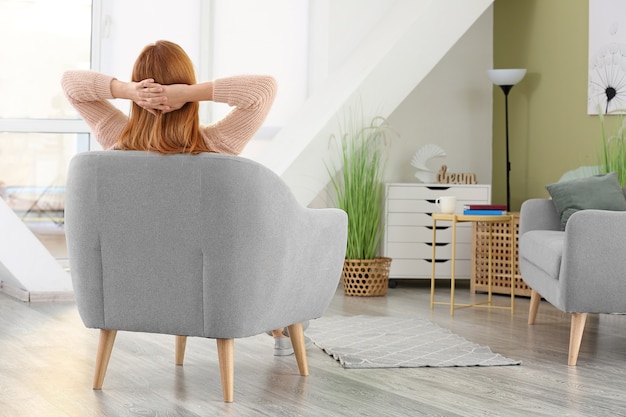 Hermosa mujer descansando en un sillón en casa