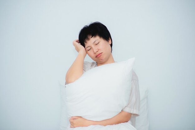 Hermosa mujer se despierta por la mañana, se estira en la cama y la almohada