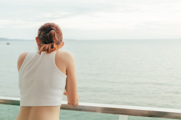 Hermosa mujer disfruta mirando la vista al mar desde el balcón del hotel