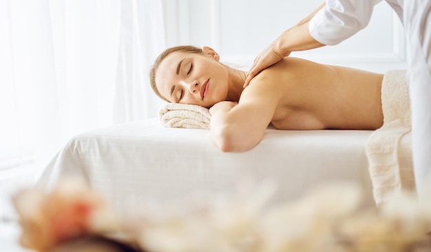 Hermosa mujer disfrutando de un masaje de espalda con los ojos cerrados. Concepto de tratamiento de spa.