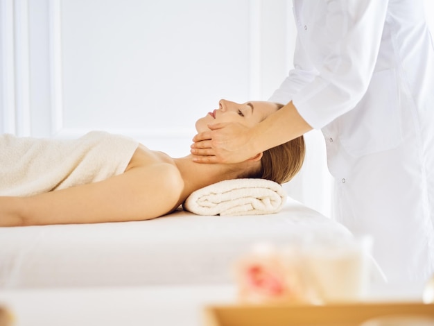 Hermosa mujer disfrutando de un masaje facial con los ojos cerrados. Concepto de tratamiento de spa en medicina.