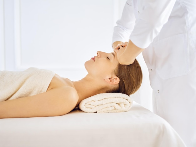 Hermosa mujer disfrutando de un masaje facial con los ojos cerrados. Concepto de tratamiento de spa en medicina.