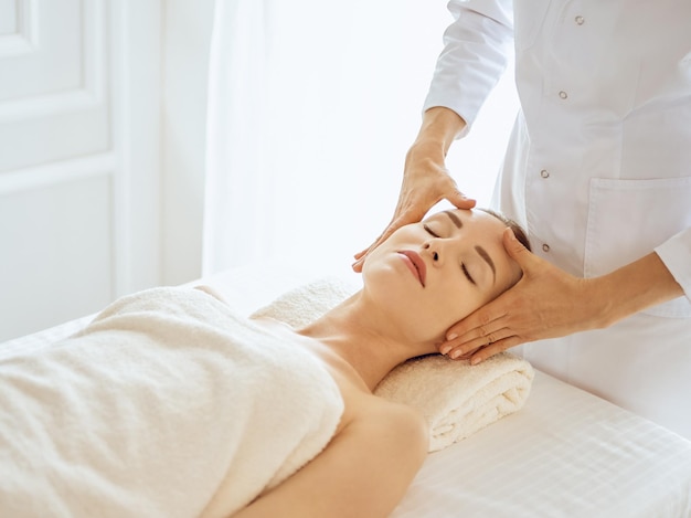 Hermosa mujer disfrutando de un masaje facial con los ojos cerrados. Concepto de tratamiento de spa en medicina.