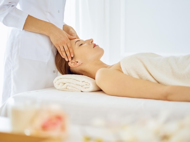 Hermosa mujer disfrutando de un masaje facial con los ojos cerrados. Concepto de tratamiento de spa en medicina.