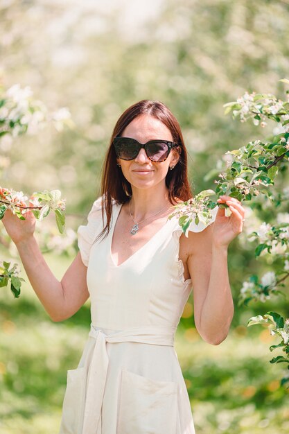 Hermosa mujer disfrutando el olor en el jardín de cerezos de primavera