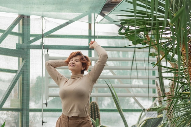 Una hermosa mujer disfrutando de pie entre las plantas verdes.