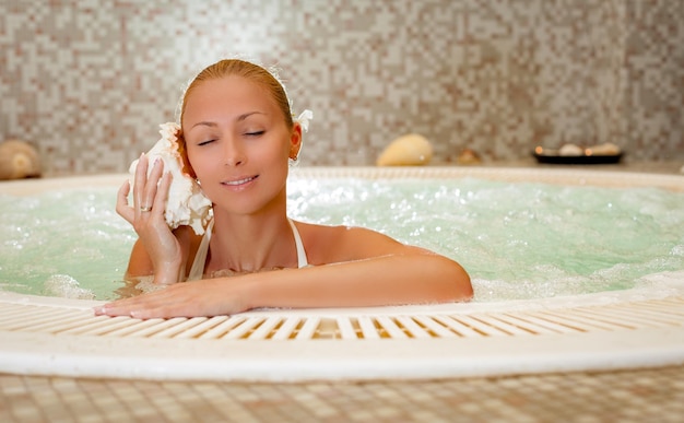 Hermosa mujer disfrutando y relajándose en el jacuzzi del centro de spa.